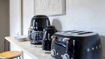 Uma bancada de cozinha com uma cafeteira, uma torradeira e uma pilha de pratos.