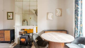 A modern living room with a round table, two chairs, a fireplace, and a large mirror.