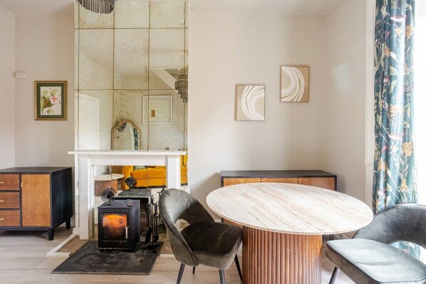 A modern living room with a round table, two chairs, a fireplace, and a large mirror.
