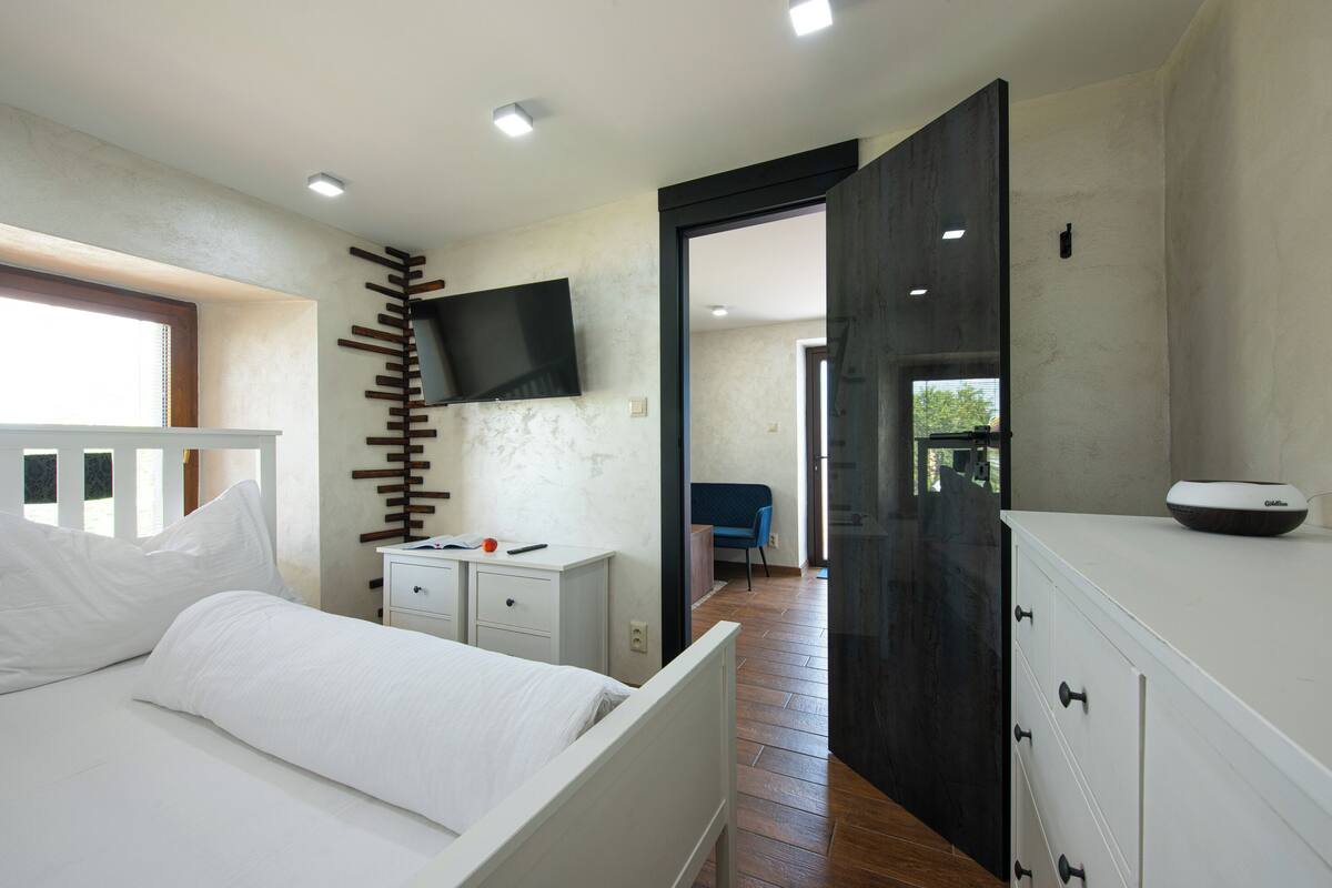 A bedroom with a bed, bedside tables, a TV mounted on the wall, and a wardrobe.