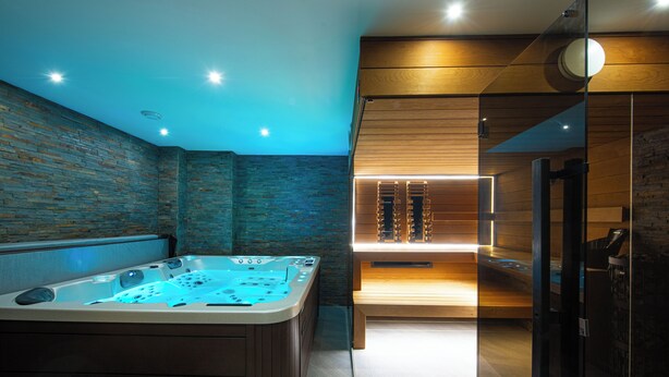 A modern spa room with a hot tub, wooden panel walls, and a glass partition. - Apartmány Žakovce & SPA (Vysoké Tatry)