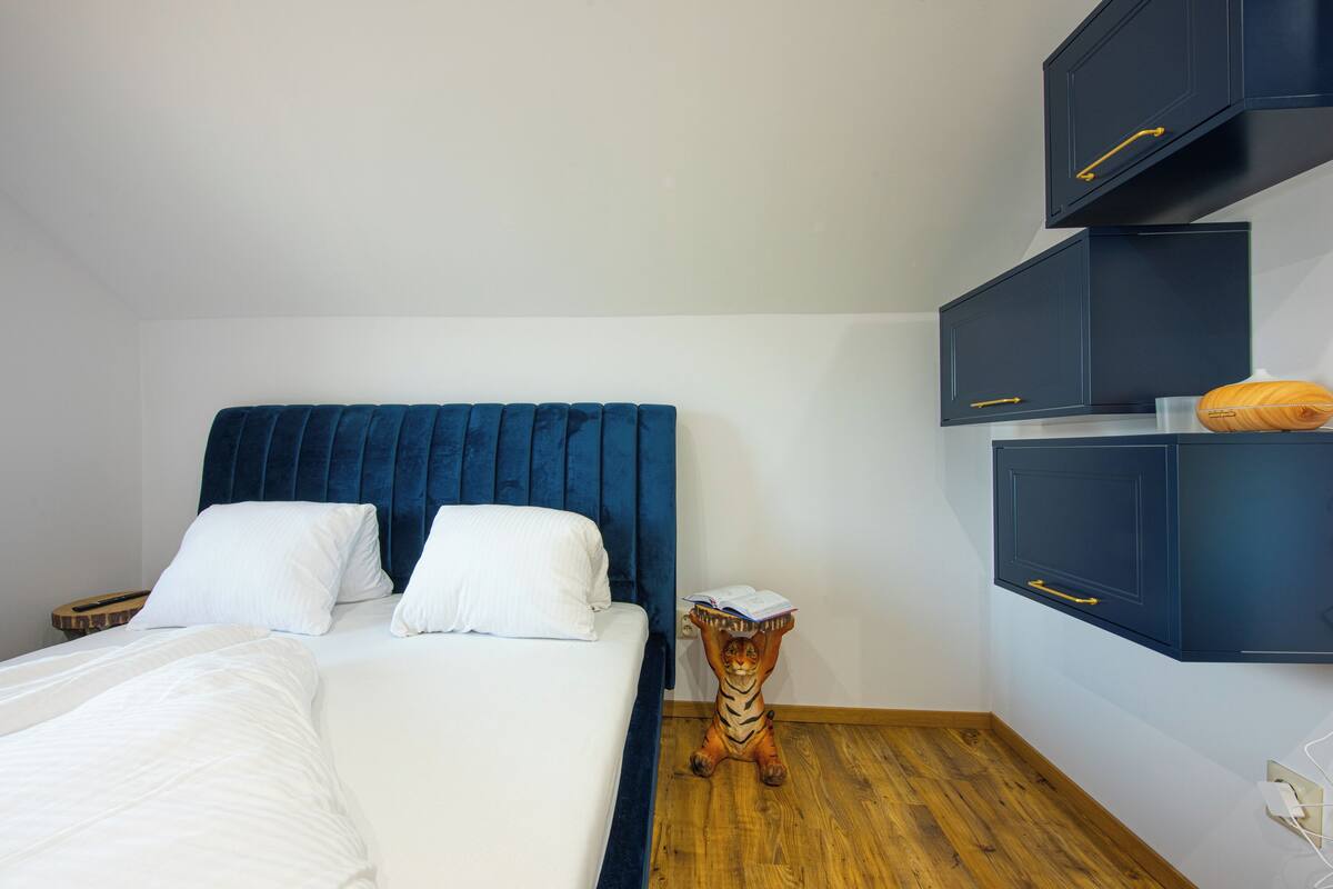 A bedroom with a bed, a nightstand, a wooden floor, and built-in cabinets.