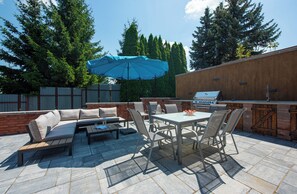 Eine Außenpatio mit integriertem Grill, einer Sitzgelegenheit und einem großen Sonnenschirm.
