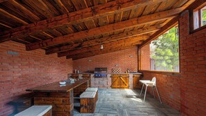 A rustic kitchen with a brick wall, wooden ceiling beams, and a stone floor. - Apartmány Žakovce & SPA (Vysoké Tatry)