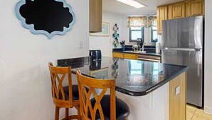 Una cucina con isola centrale, mobili in legno, frigorifero in acciaio inossidabile e un elemento decorativo a parete.