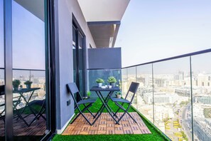 A balcony with a table and chairs, a small potted plant, and a view of a cityscape. - Bloomfields 1Br Binghatti Heights (Dubai)