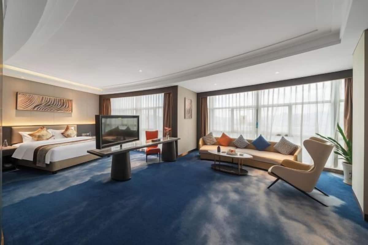 Una habitación de hotel con cama, televisor, sofá y mesa de centro.