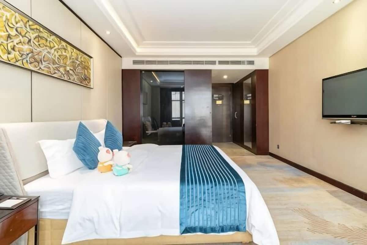 Una habitación de hotel con una cama, un televisor y un cuadro en la pared.