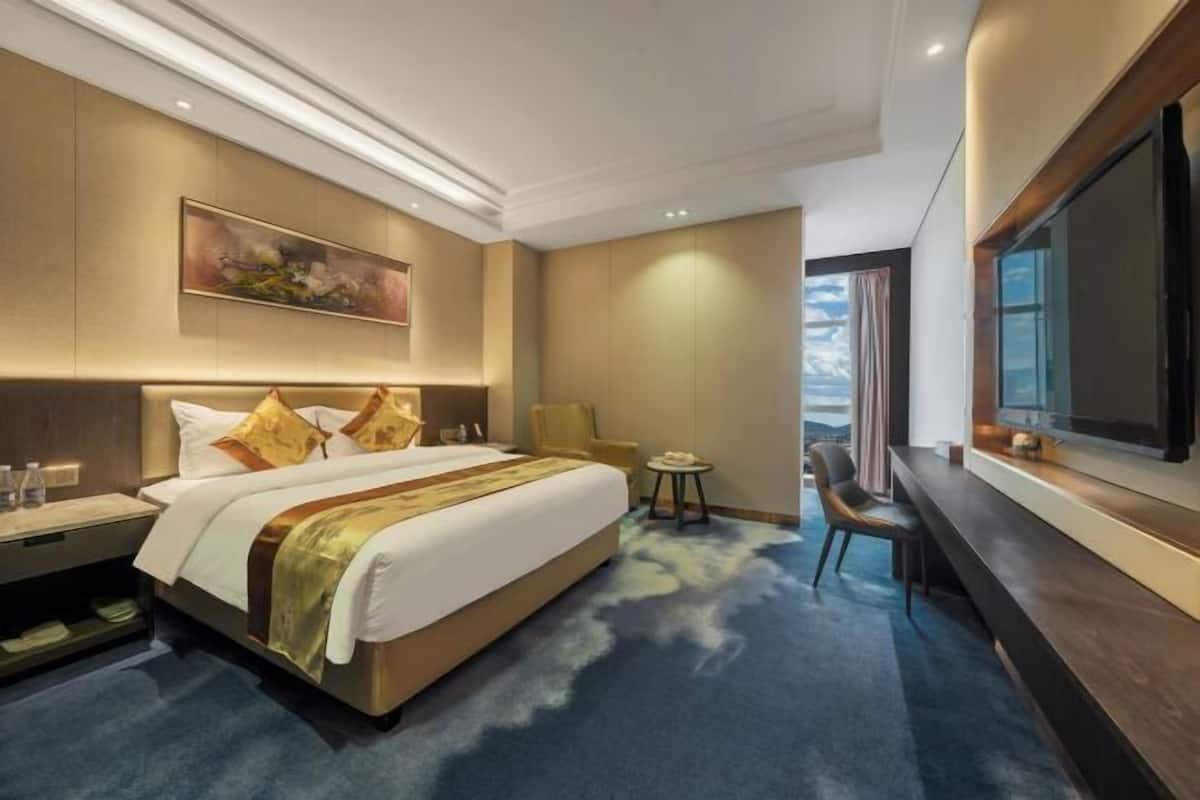 Habitación de hotel con una cama grande, un televisor de pantalla plana, una mesita y una silla.