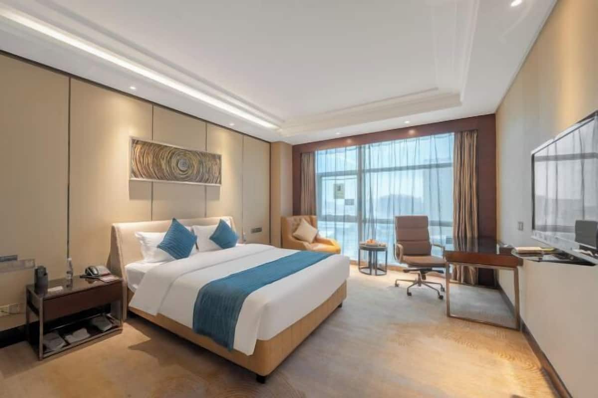 Una habitación de hotel con cama, escritorio, silla y televisor.