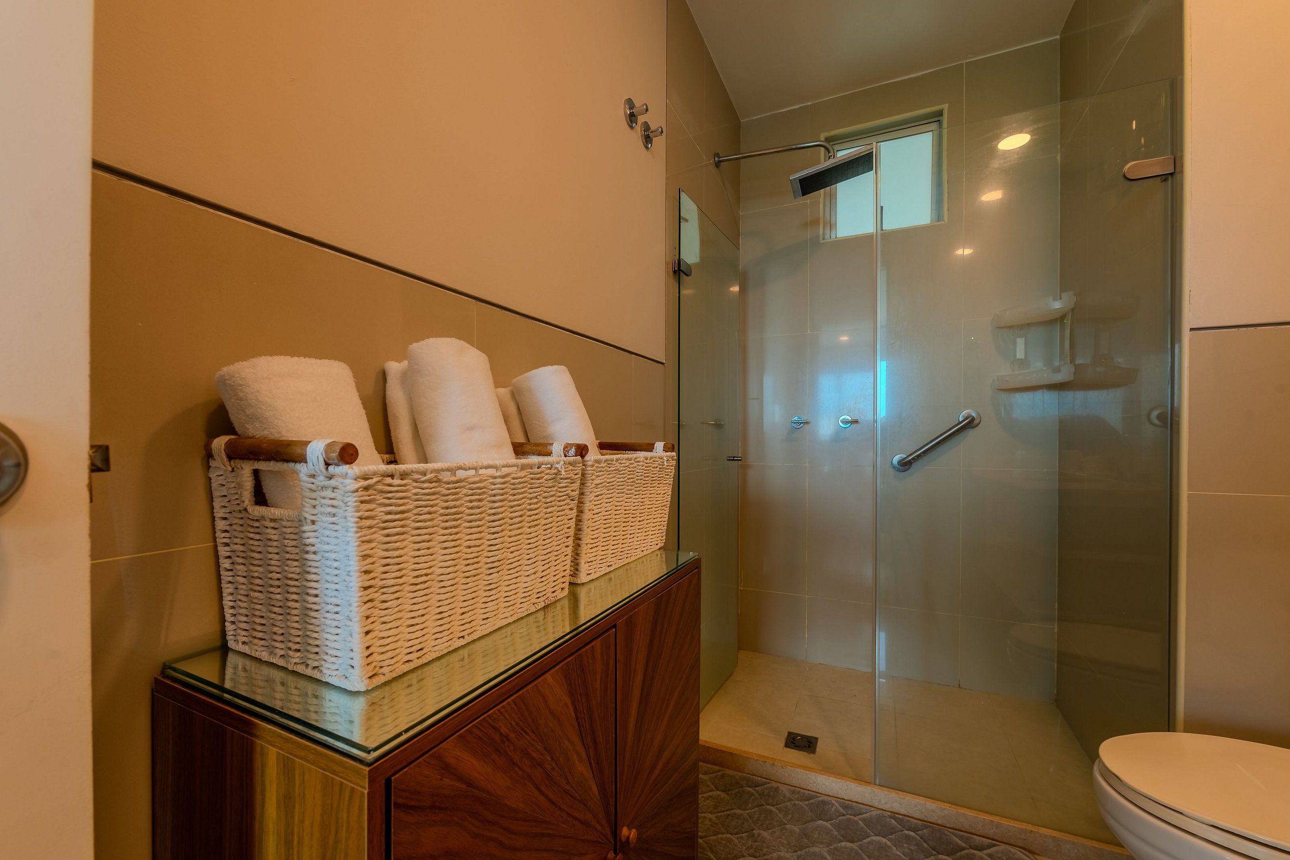 Ein Badezimmer mit Duschkabine, Toilette und Waschtisch mit Spiegel und Handtuchhaltern.