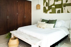 A bedroom with a large bed, a wooden wardrobe, a woven lamp, and a green abstract wall art. - Condominio frente al mar  Morros Epic. (Cartagena)