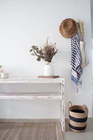 A white, distressed wooden bench with a woven basket and a white vase with dried flowers on a white wall. - Condominio frente al mar  Morros Epic. (Cartagena)