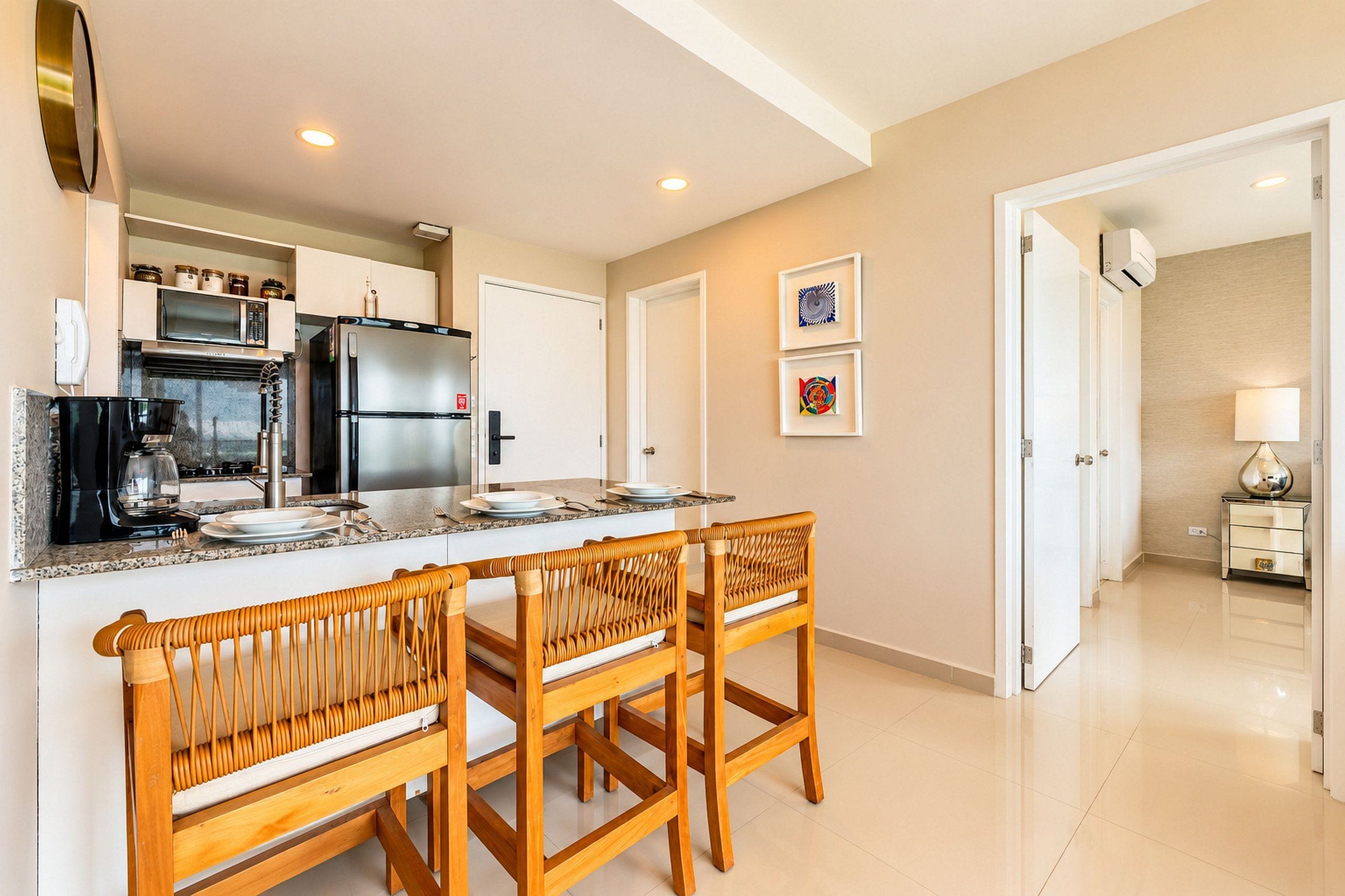 Una cocina moderna con una isla central, electrodomésticos de acero inoxidable y un comedor con sillas de madera.