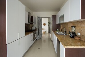 A modern kitchen with white cabinets, a granite countertop, and stainless steel appliances. - Condominio frente al mar  Morros Epic. (Cartagena)