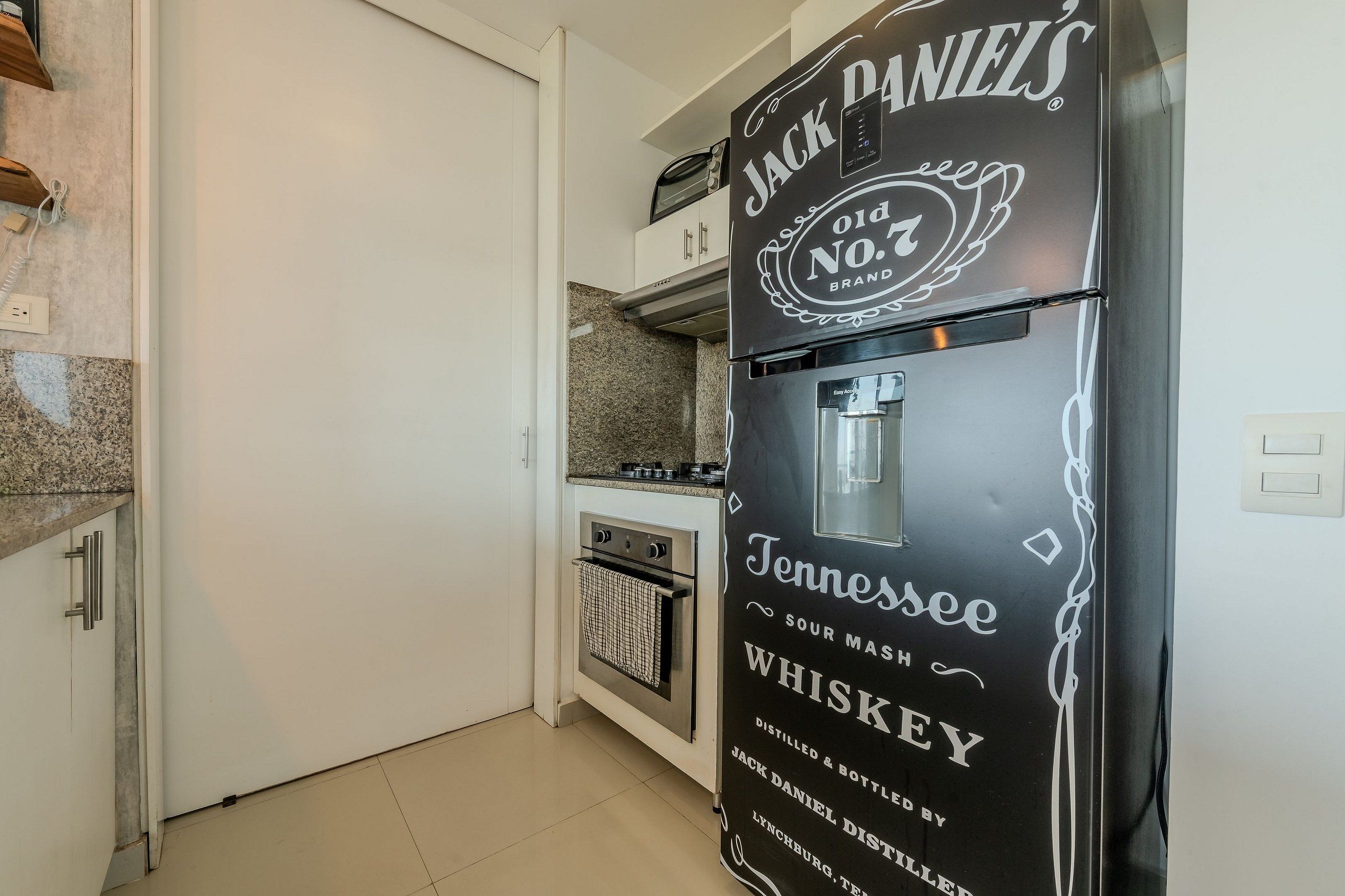 A kitchen with a refrigerator labeled 'Jack Daniel's Old No. 7 Brand Tennessee Sour Mash Whiskey.'