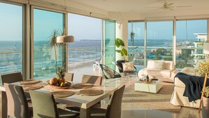 A spacious living area with a balcony overlooking the sea, featuring a dining table, seating, and a modern ceiling fan. - Condominio frente al mar  Morros Epic. (Cartagena)