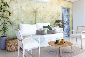 A modern living room with a sofa, two armchairs, a coffee table, and a large potted plant. - Condominio frente al mar  Morros Epic. (Cartagena)