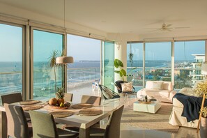 A spacious living area with a balcony overlooking the sea, featuring a dining table, seating, and a modern ceiling fan. - Condominio frente al mar  Morros Epic. (Cartagena)