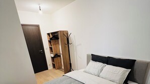 A bedroom with a bed, a wooden wardrobe, a coat rack, and a black bag. - Liège city charm - Opera view (Liège)