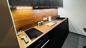 A modern kitchen with a wooden countertop, a built-in oven, and a black stovetop. - Liège city charm - Opera view (Liège)