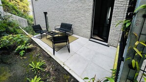 A patio with a brick wall, a black door, and outdoor furniture. - Liège city charm - Opera view (Liège)