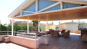 An outdoor patio with a covered seating area, a pool, and a bar. - Villa Berria (Marratxí)