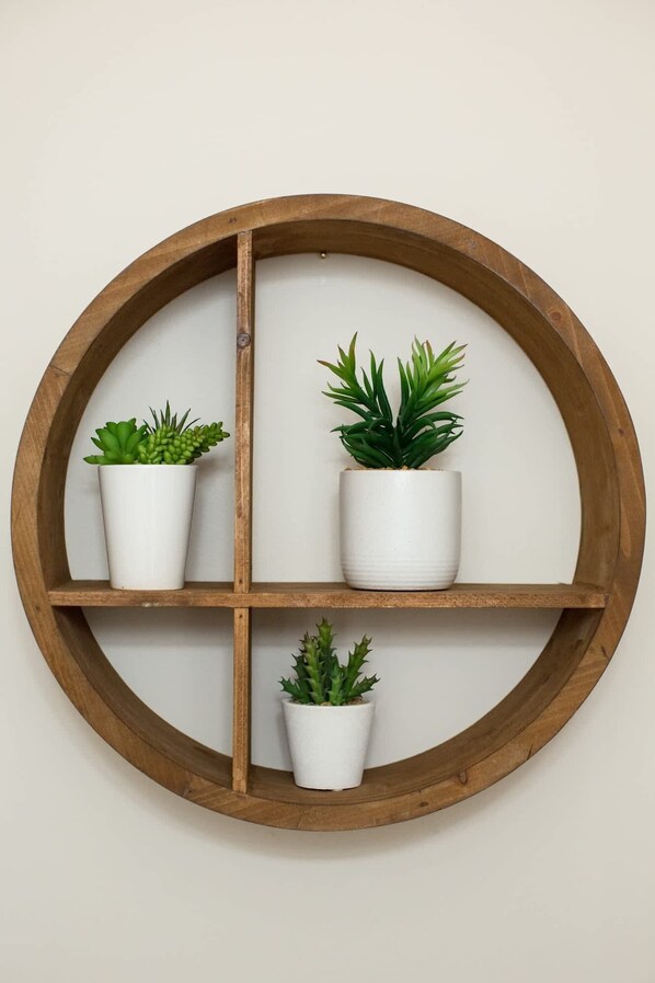 Une étagère circulaire en bois, sur laquelle reposent quatre pots blancs contenant différents types de plantes succulentes.