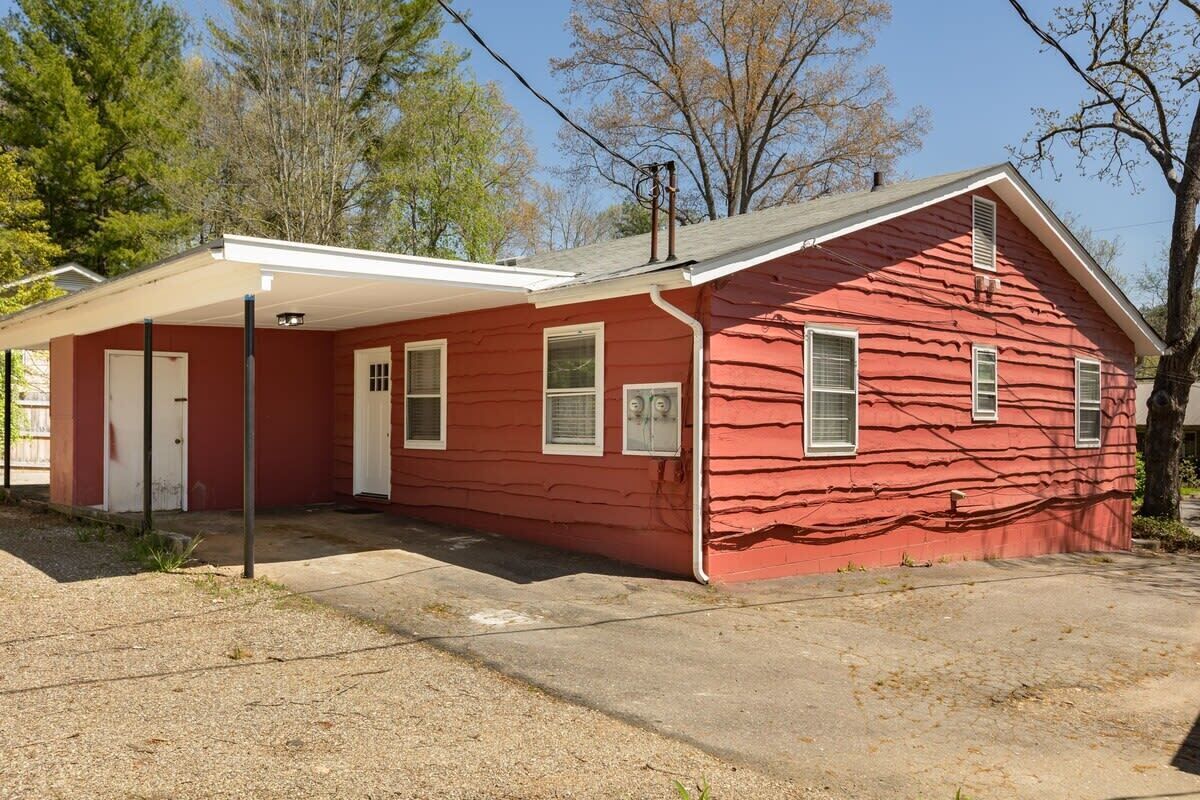 Une maison rouge à un étage, dotée d’un porche abrité, d’une porte d’entrée et d’un petit garage.