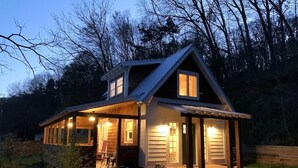 Une maison en bois à deux étages, dotée d’un porche abrité et d’un petit jardin.