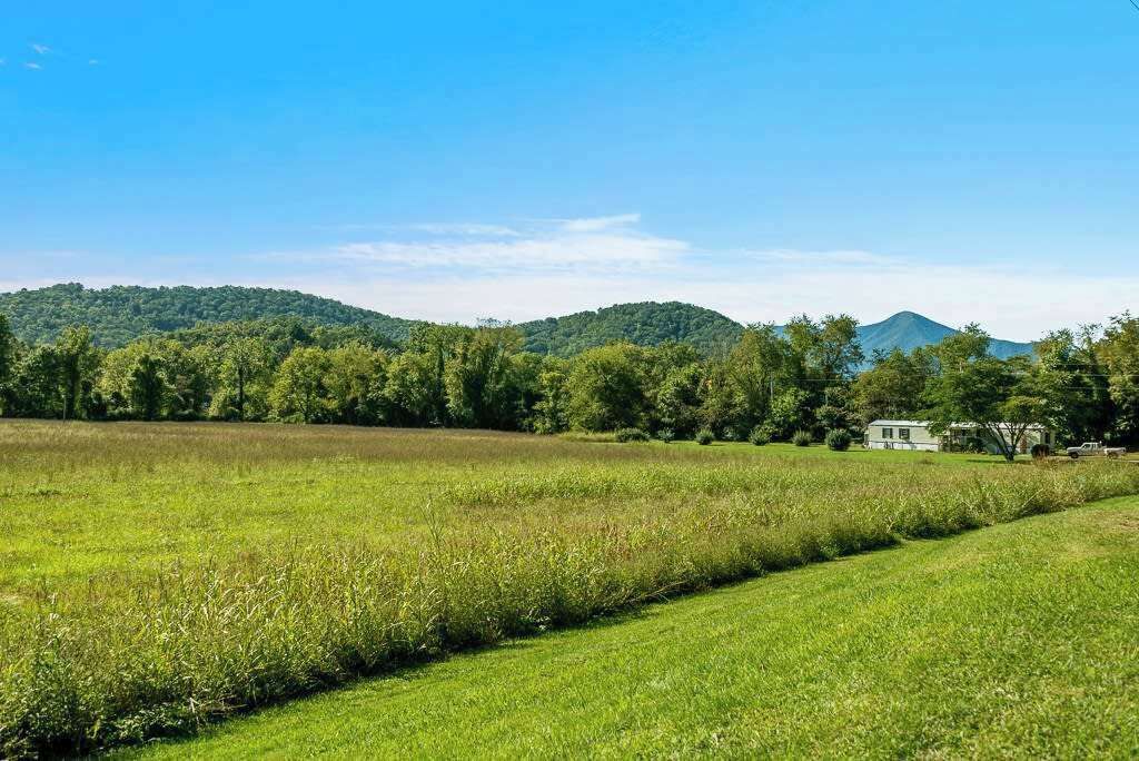 A rural landscape with a house in the distance, surrounded by lush green fields and trees.