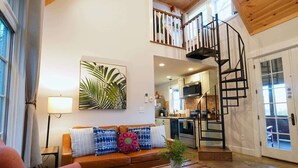 Un vaste espace de vie comprenant un canapé, une table basse en bois et un escalier menant à un niveau supérieur.