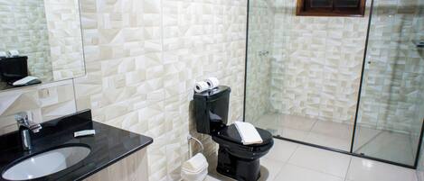 A modern bathroom with a black sink, a toilet, and a glass shower enclosure.