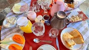 A breakfast table with various food items and drinks, including bread, cheese, and a pitcher of juice. - Pousada Sol Nascente (Camanducaia)