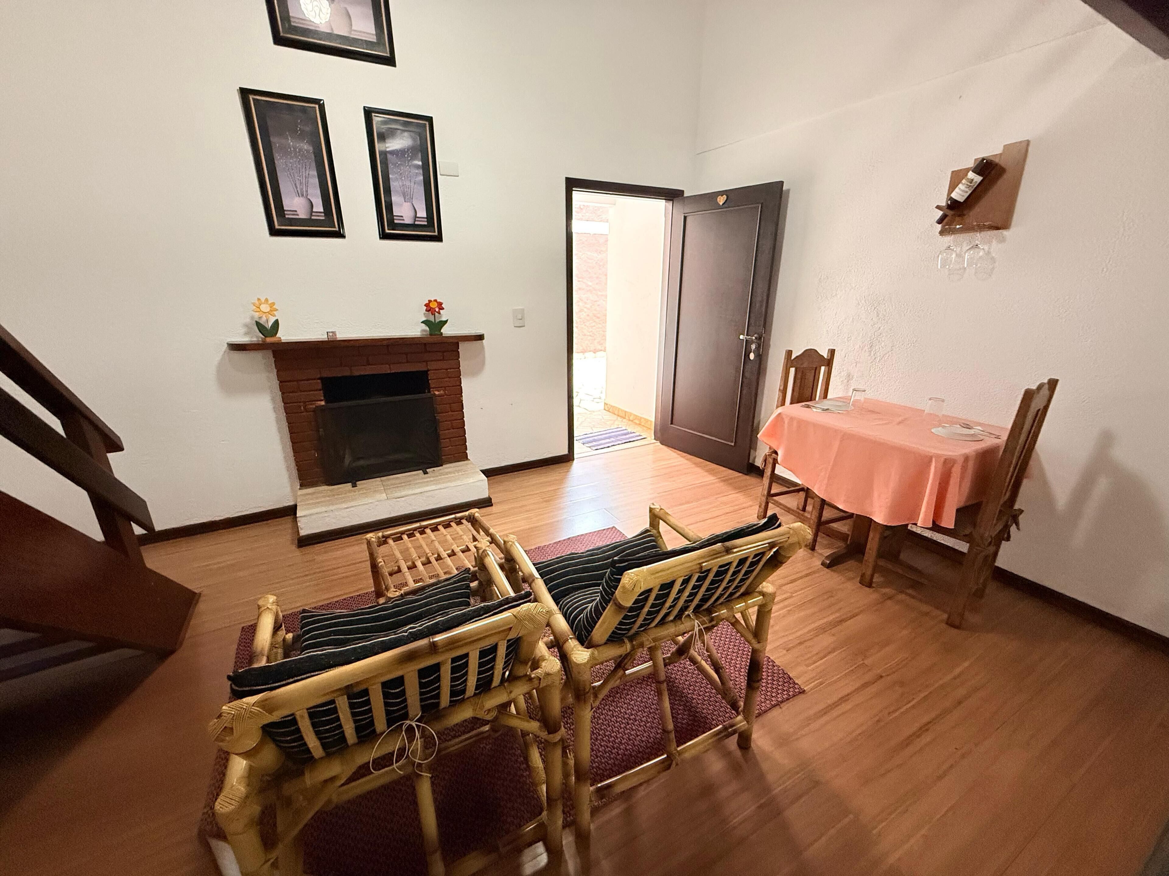 A dining area with a table set for two, a fireplace, and a door leading to another room.