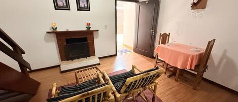 A dining area with a table set for two, a fireplace, and a door leading to another room.