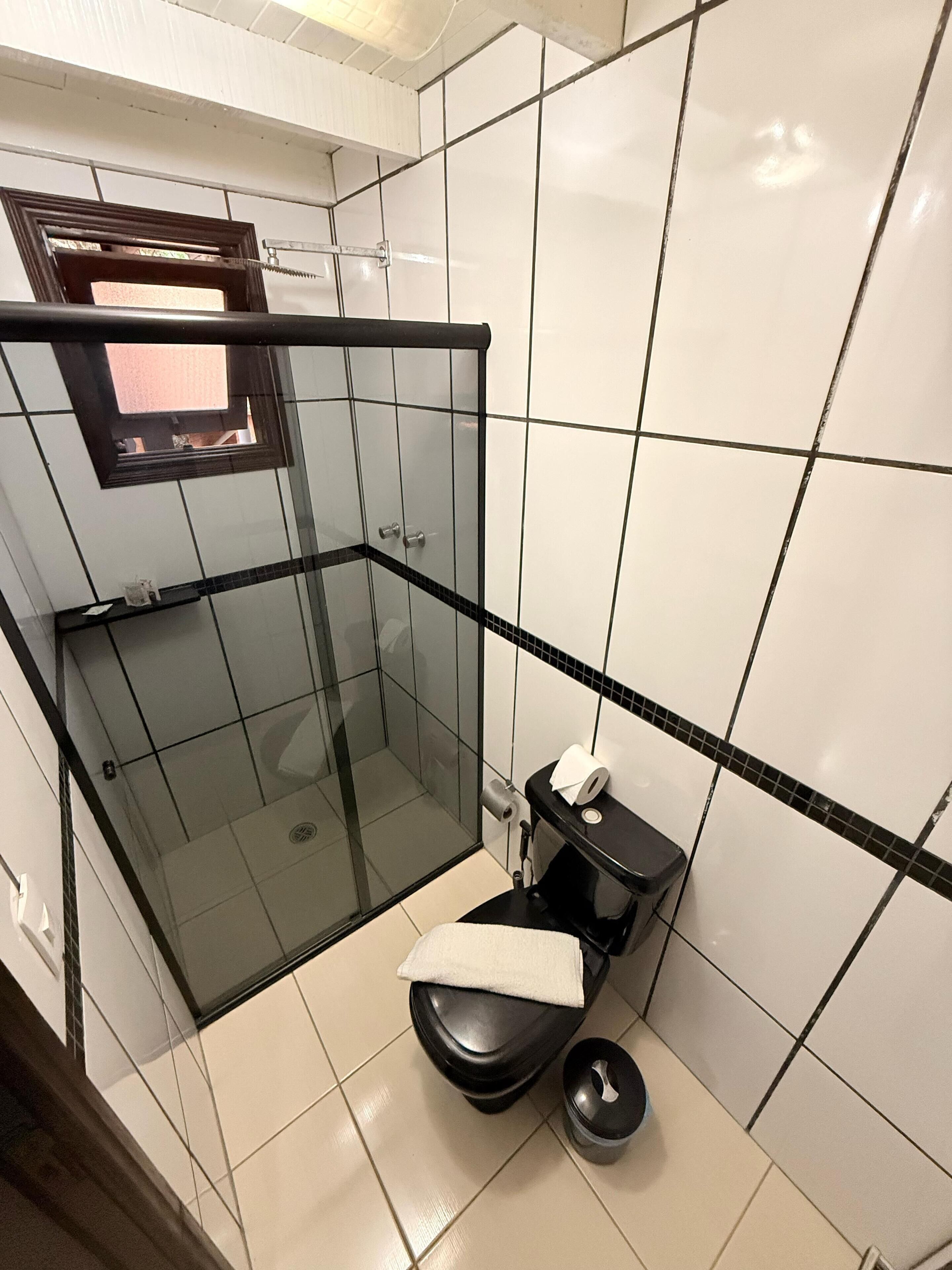 A bathroom with a glass-enclosed shower, a toilet, and a sink.