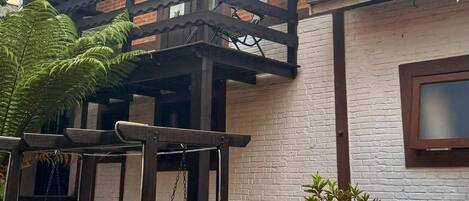 A building with a brick facade, a balcony with a wooden railing, and a window with a frosted glass pane.