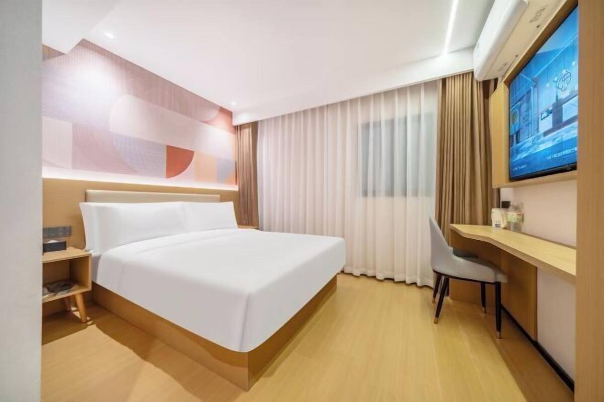 Una habitación de hotel con cama, escritorio, silla y televisor.