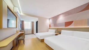 Ein Hotelzimmer mit Schreibtisch, zwei Betten, einem Spiegel und Blick auf den Korridor.