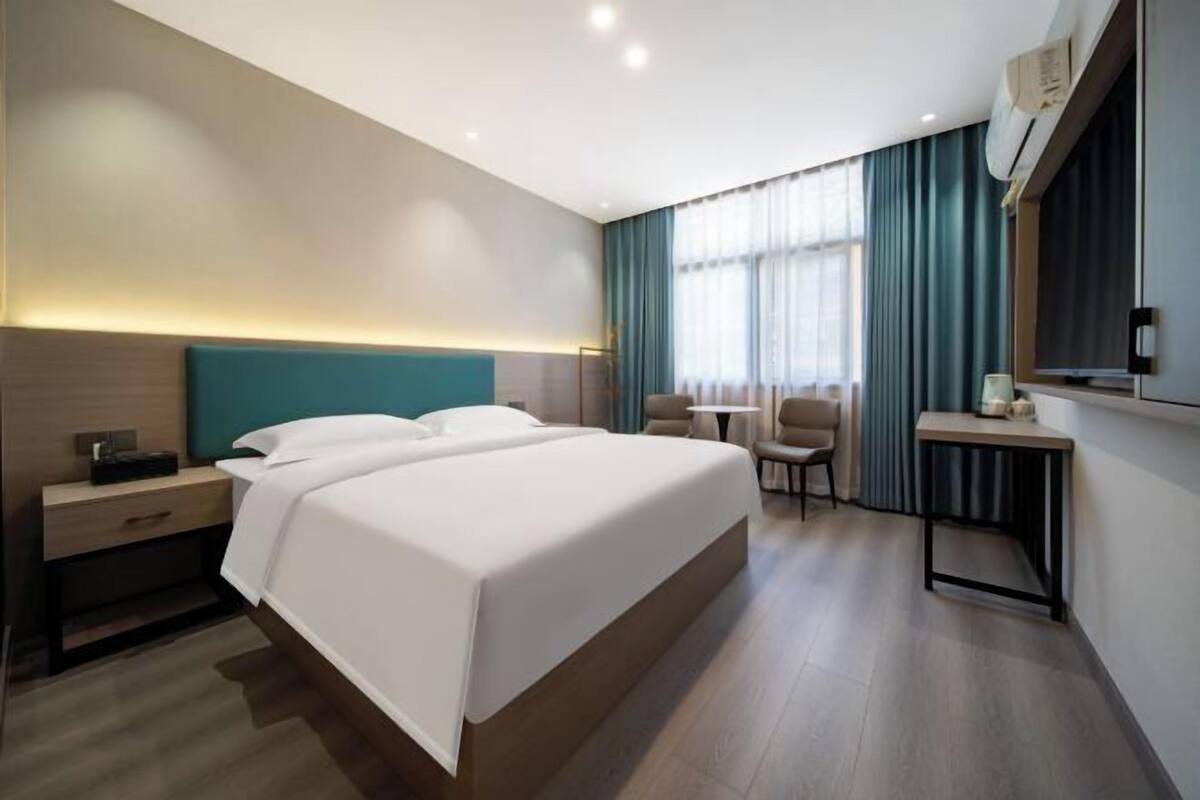 Una habitación de hotel moderna con una cama grande, un escritorio y una silla.