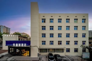 Un edificio de hotel de varios pisos con fachada plana, múltiples ventanas y un estacionamiento al frente.