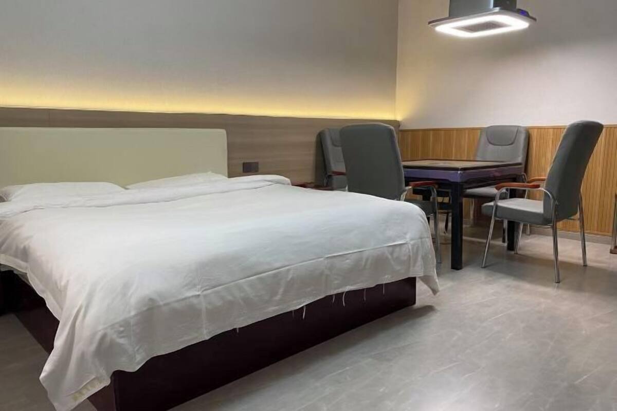 Habitación de hotel con una cama grande, un escritorio con dos sillas y una lámpara moderna sobre el escritorio.