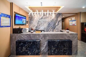 A reception desk with a marble counter, a television screen, and informational posters on the walls.
