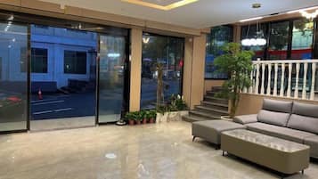A modern lobby with a sofa, a coffee table, and a staircase leading to an outdoor area.