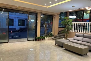 A modern lobby with a sofa, a coffee table, and a staircase leading to an outdoor area.