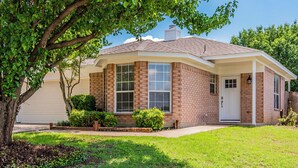A two-story house with a brick exterior, a front porch, and a garage. - Lone Star Haven for 8 (Burleson)