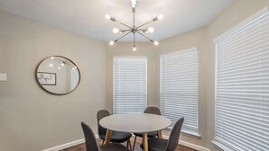 A conference room with a round table, six chairs, a ceiling light fixture, and three windows with blinds. - Lone Star Haven for 8 (Burleson)