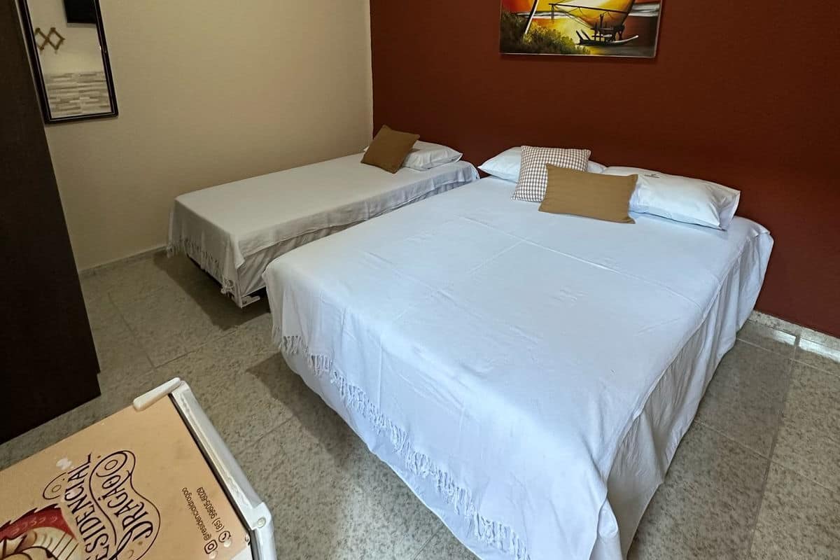 Habitación de hotel con dos camas individuales, un cuadro grande de un atardecer y un cuadro en la pared.
