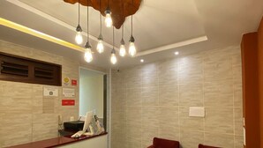 Zona de recepción con techo de madera, mostrador de recepción y tres sillas rojas.